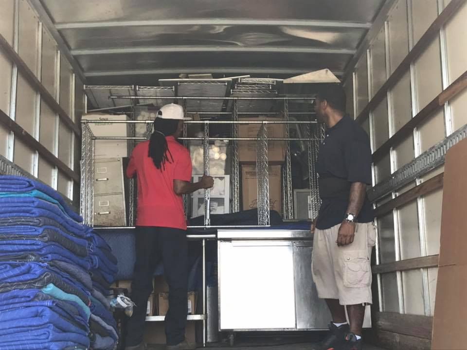 Two men are standing in the back of a moving truck 28.4845° N, 81.2519° W