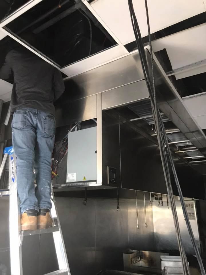 A man is standing on a ladder working on a ceiling. 28.4845° N, 81.2519° W