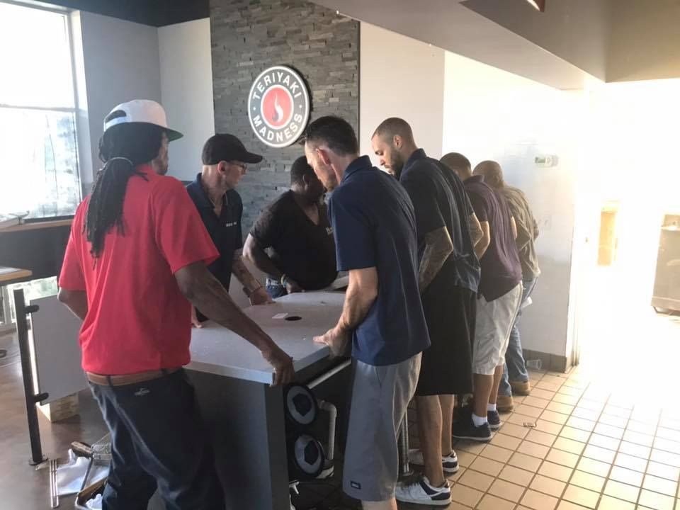 A group of people are standing around a counter in a restaurant. 28.4845° N, 81.2519° W