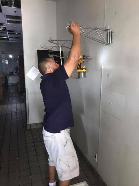 A man in a blue shirt and white shorts is working on a wall. 28.4845° N, 81.2519° W