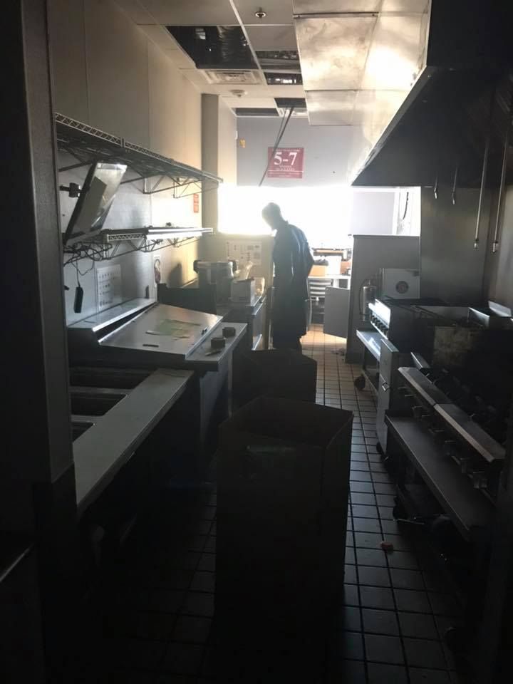 A man in a kitchen with a sign that says 28.4845° N, 81.2519° W