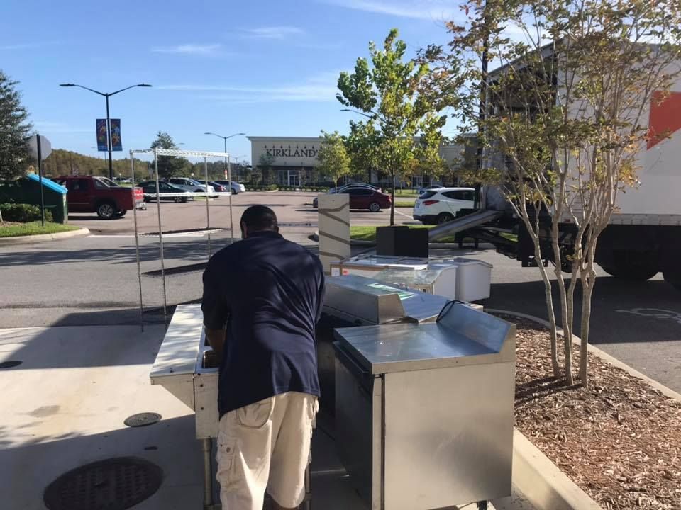 A man in a blue shirt is standing next to a stainless steel counter in a parking lot 28.4845° N, 81.2519° W