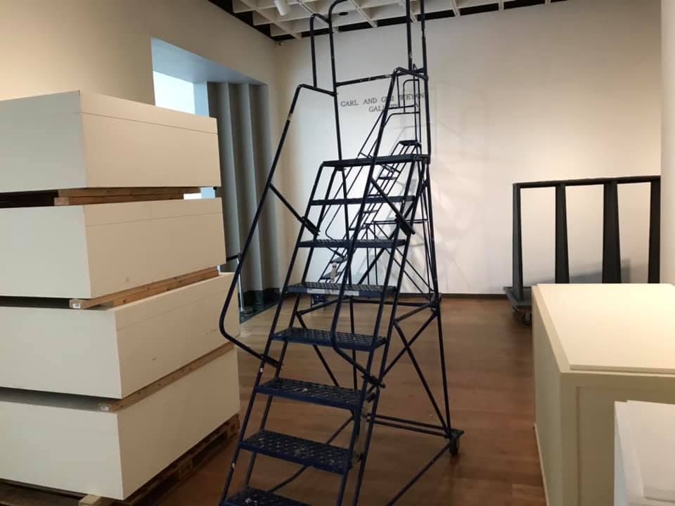 A ladder is sitting in a room next to a stack of white boxes 28.4845° N, 81.2519° W