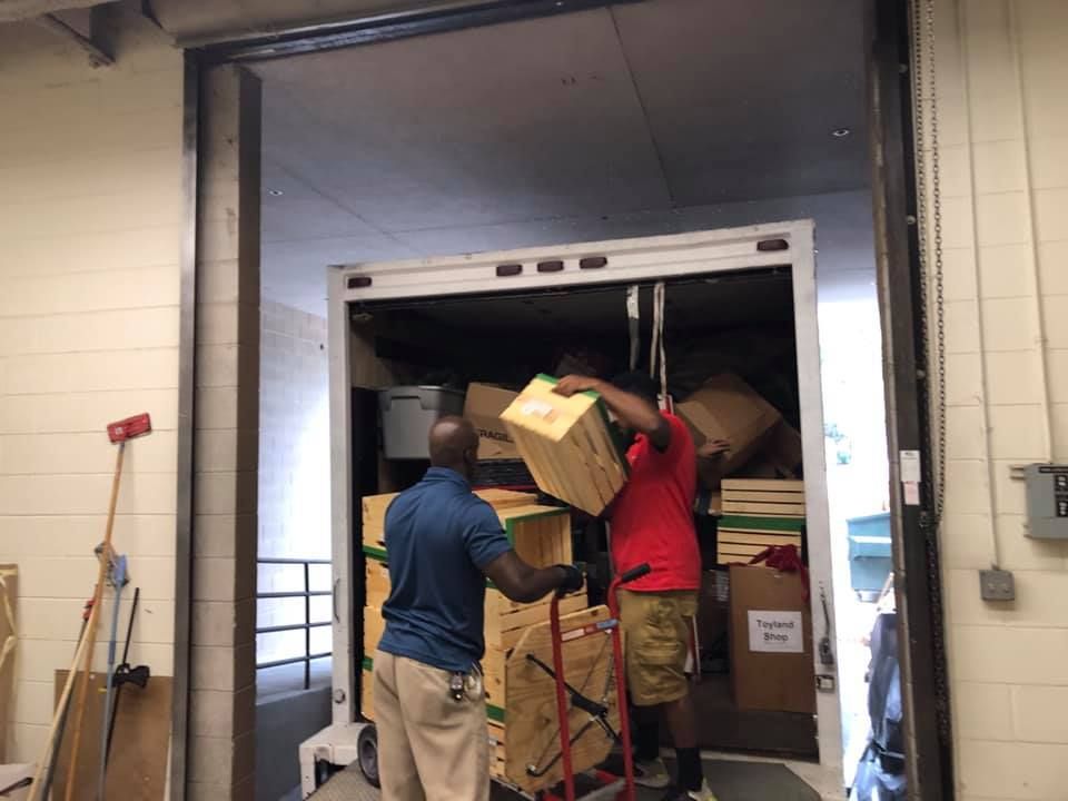 Two men are loading boxes into a truck in a warehouse 28.4845° N, 81.2519° W