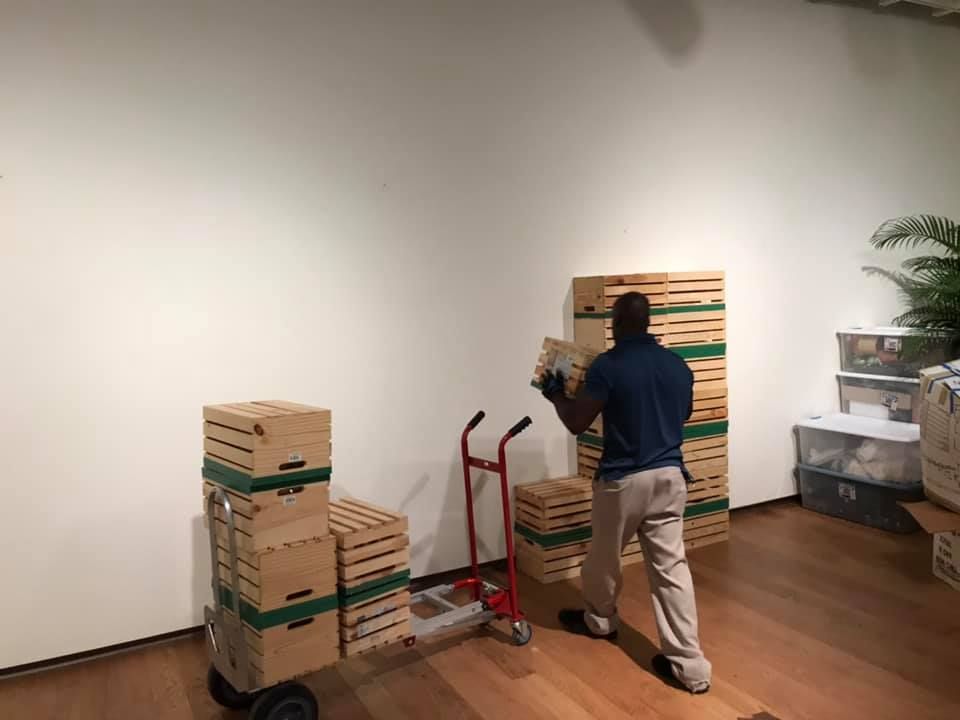 A man is pushing a cart full of boxes in a room. 28.4845° N, 81.2519° W