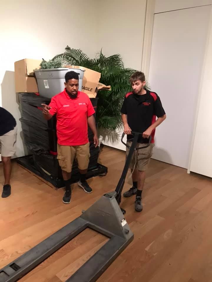 Two men are standing next to a pallet truck in a room. 28.4845° N, 81.2519° W