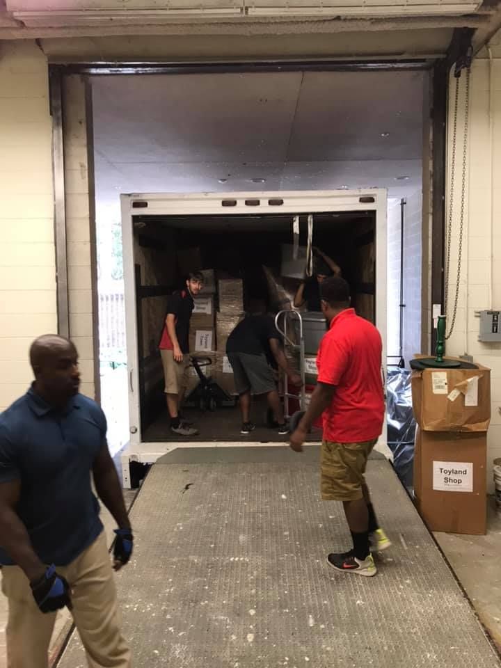 A group of men are loading boxes into a truck. 28.4845° N, 81.2519° W