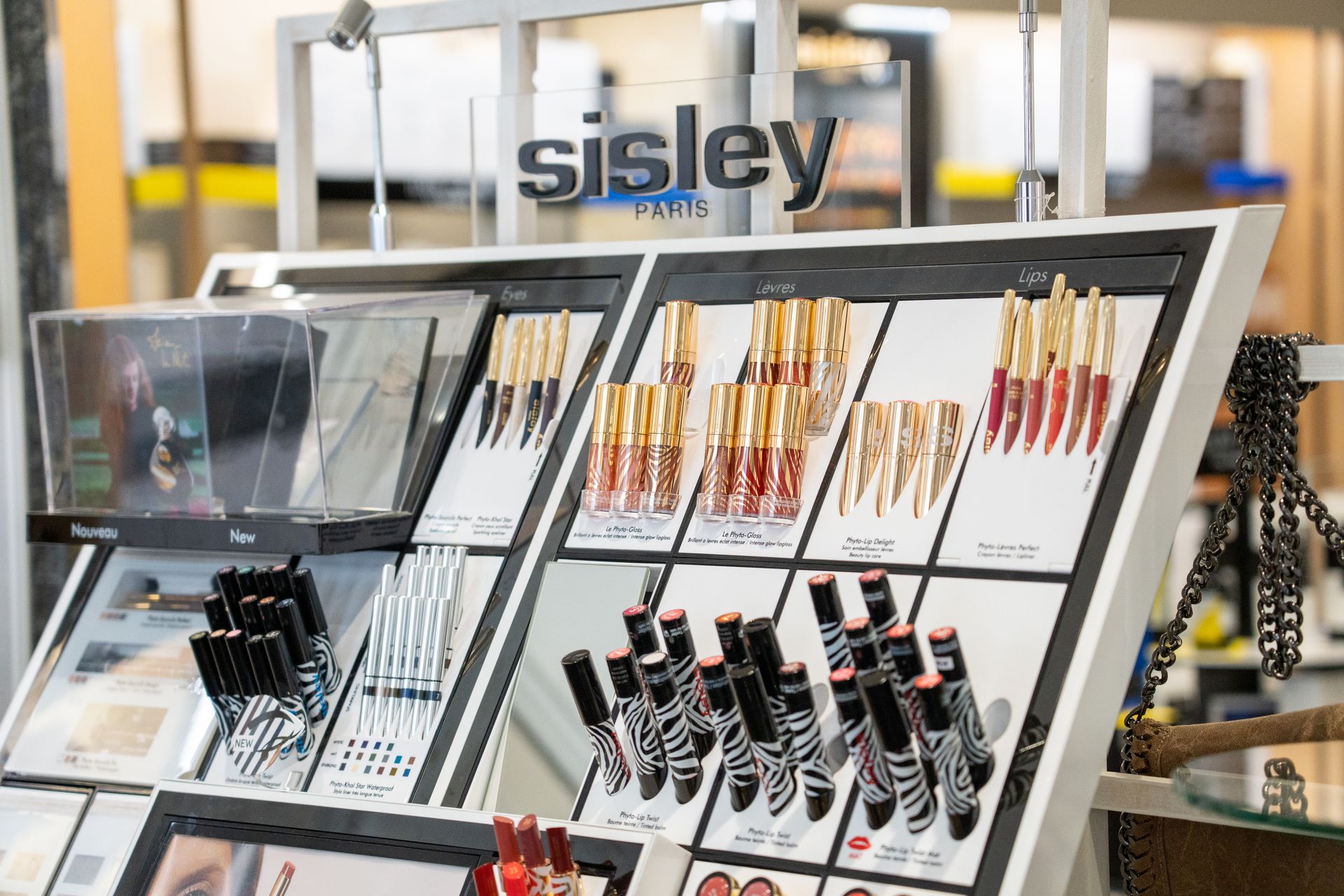 Sisley Paris Verkaufsdisplay mit Lipglosses und Lippenstiften auf gestaffelten Regalen, elegante Produktpräsentation Store.