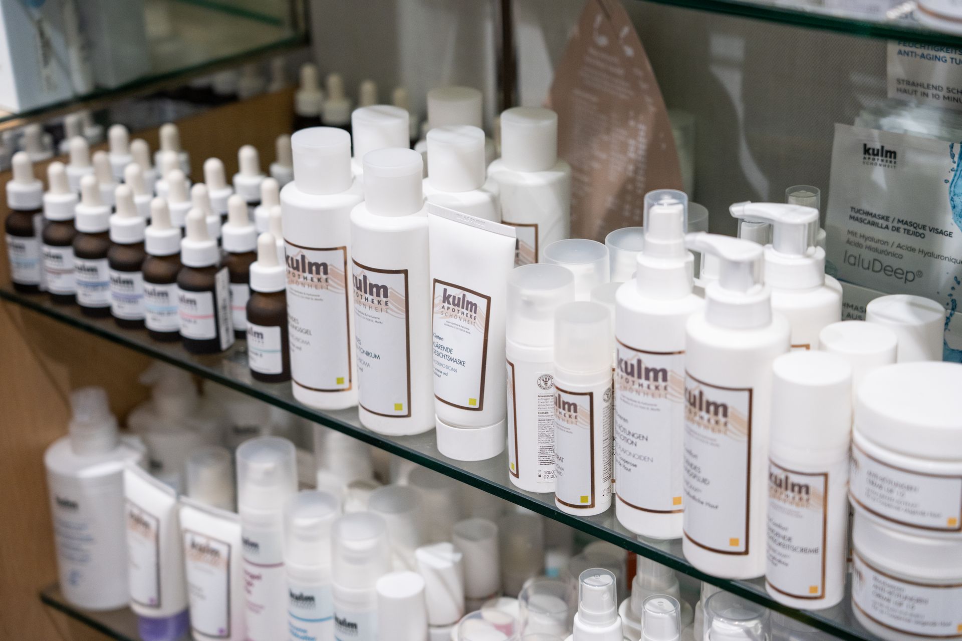 Regale gefüllt mit verschiedenen weissen Fläschchen und Tiegeln für Hautpflegeprodukte mit minimalistischen Etiketten.