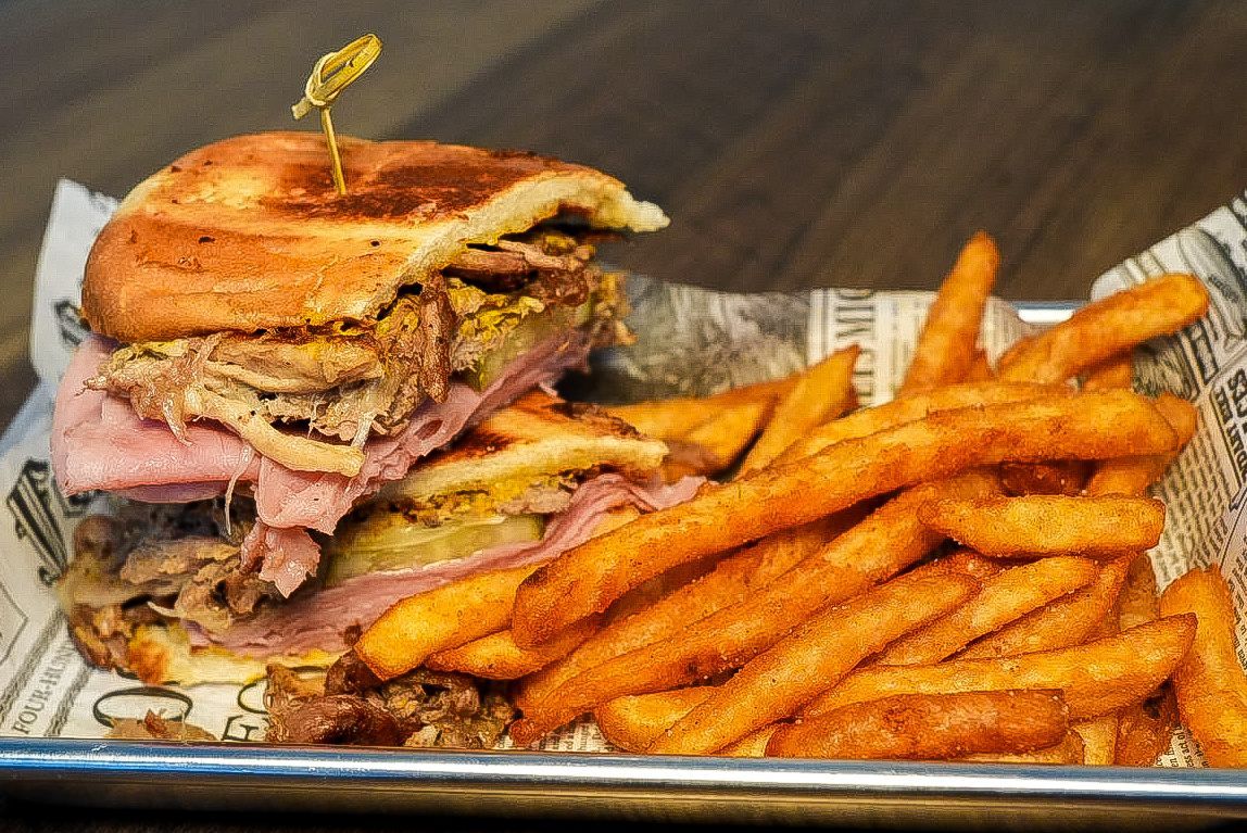 Dalmatian dog sniffs a colorful tray of fruit, including figs, raspberries, and kiwi. White background.