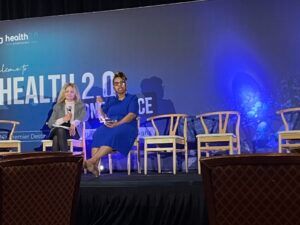 Two women are sitting on a stage at a health conference.