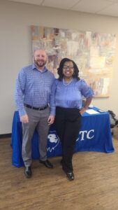 A man and a woman are standing next to each other in front of a table.