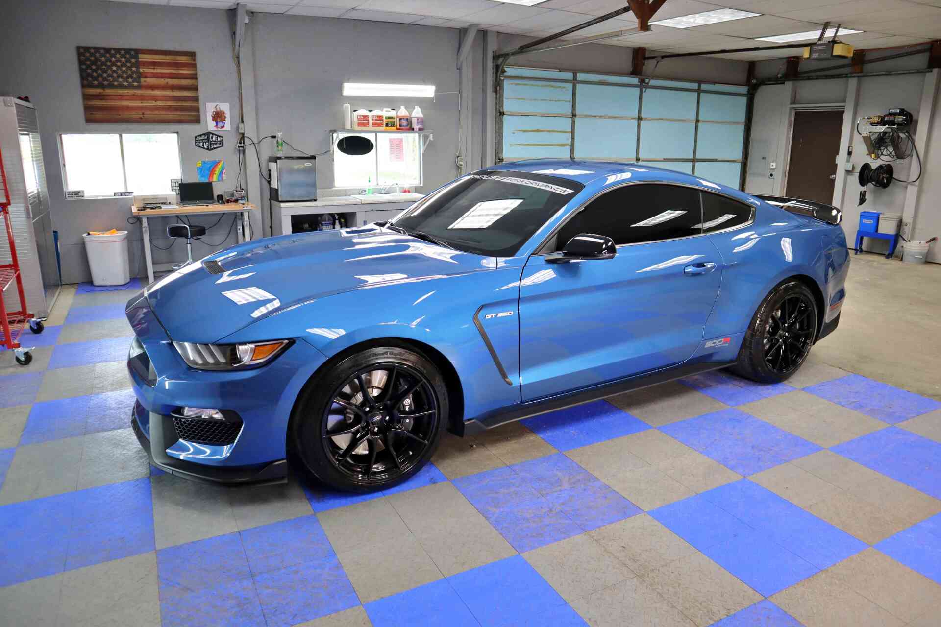 A blue ford mustang is parked in a garage.