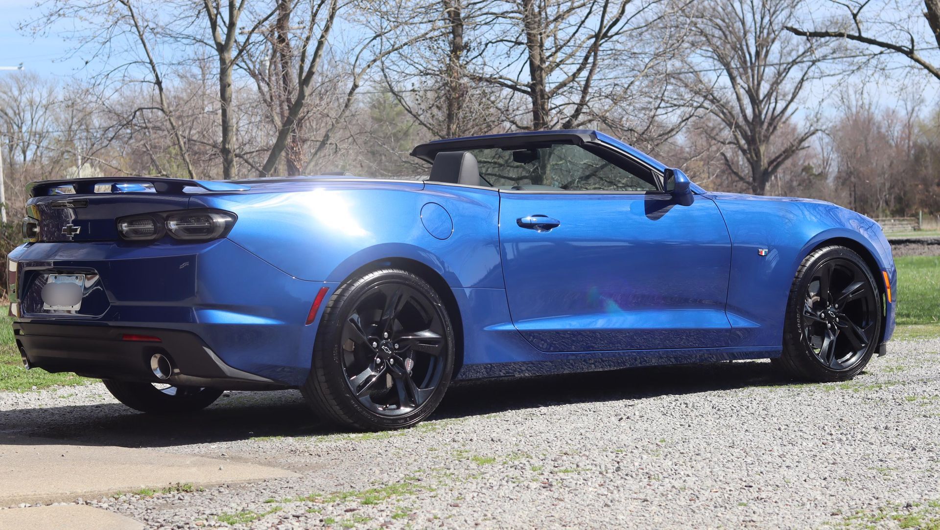 Blue convertible sports car parked outdoors on a sunny day, side view.
