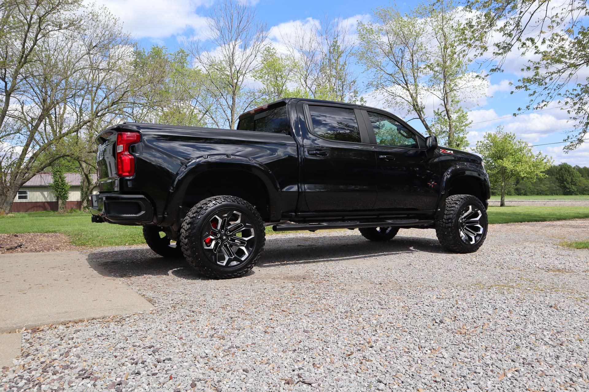 A black truck is parked on a gravel road.