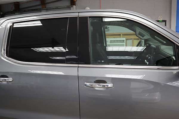 A silver truck is parked in a garage with its doors open.