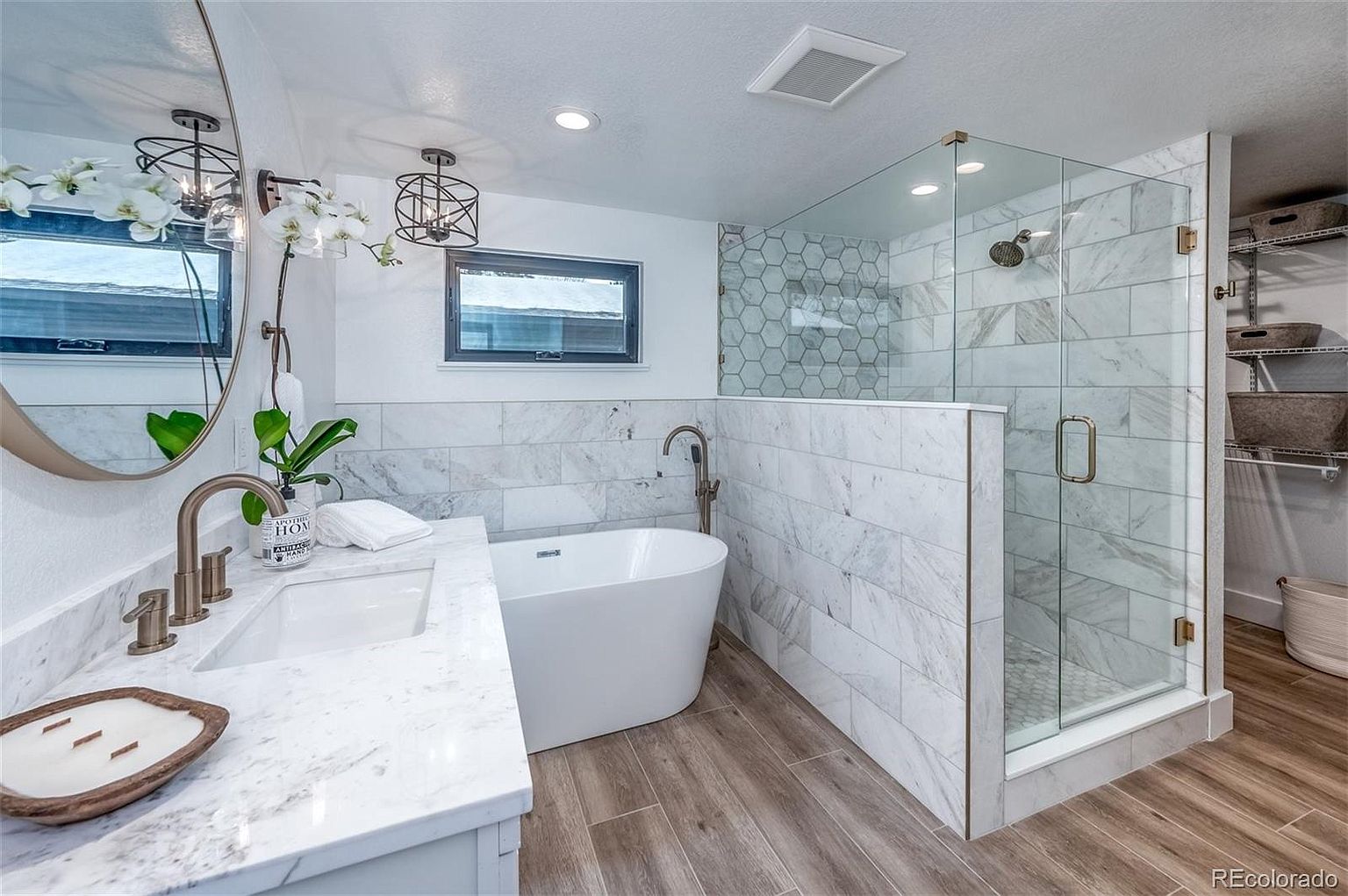 A bathroom with a tub , sink , shower and mirror.