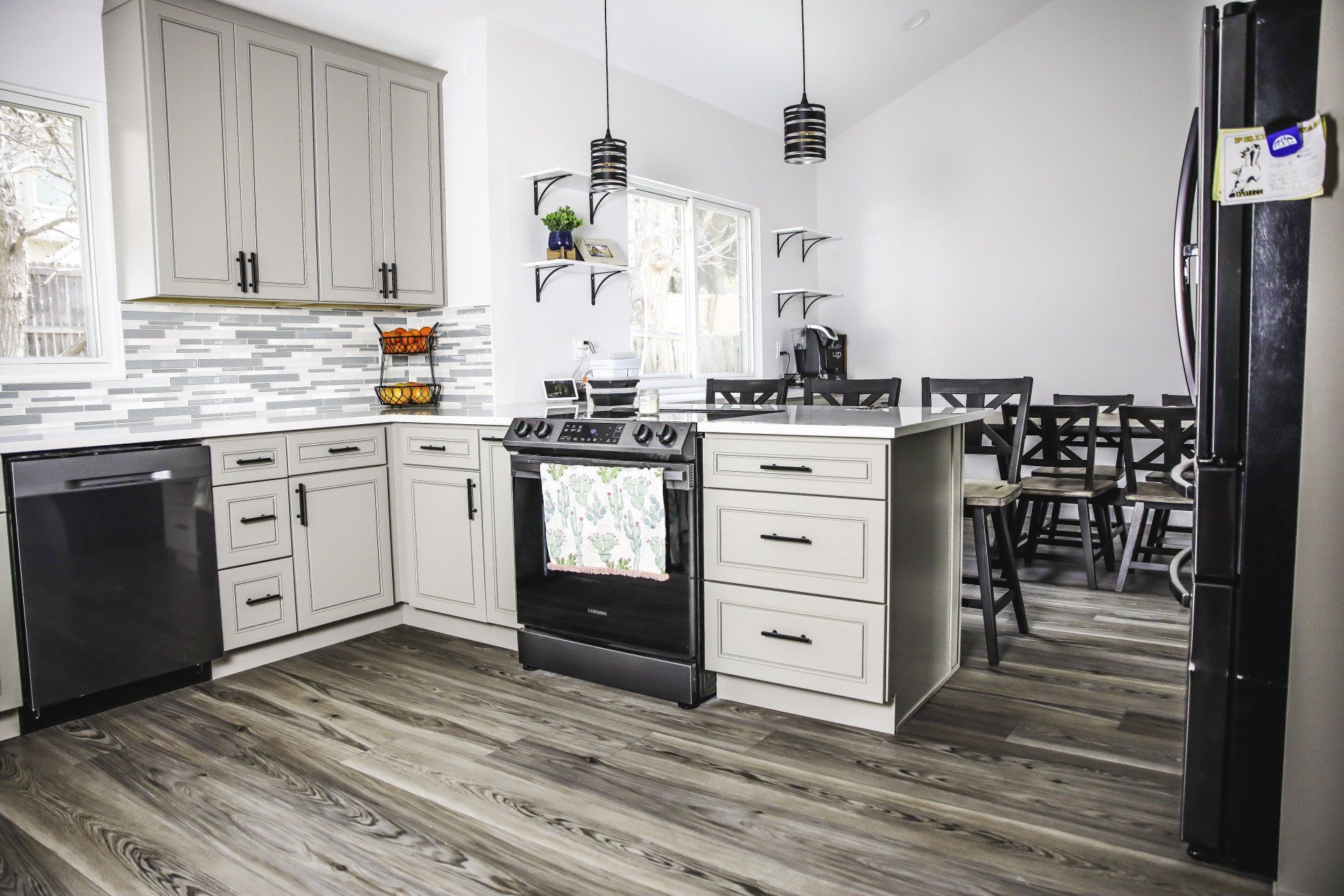 A kitchen with white cabinets , black appliances , and a large island.
