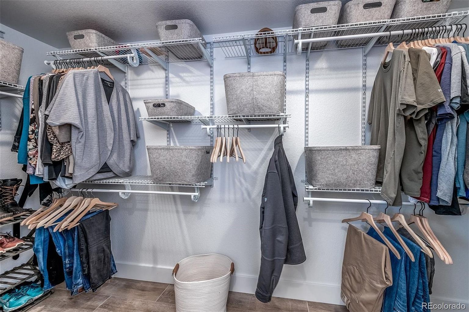 A walk in closet filled with clothes and baskets.