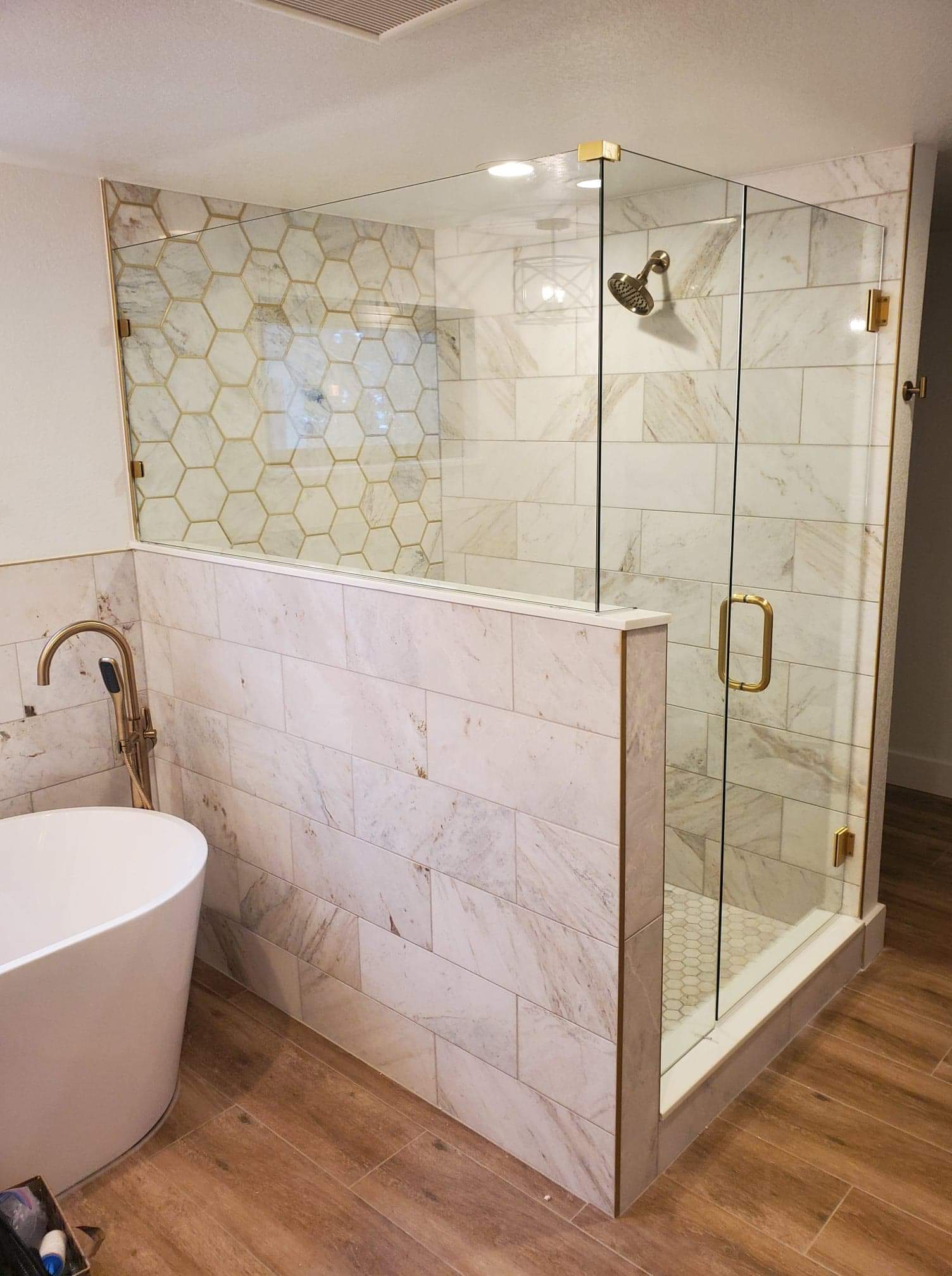 A bathroom with a tub and a shower with a glass door.