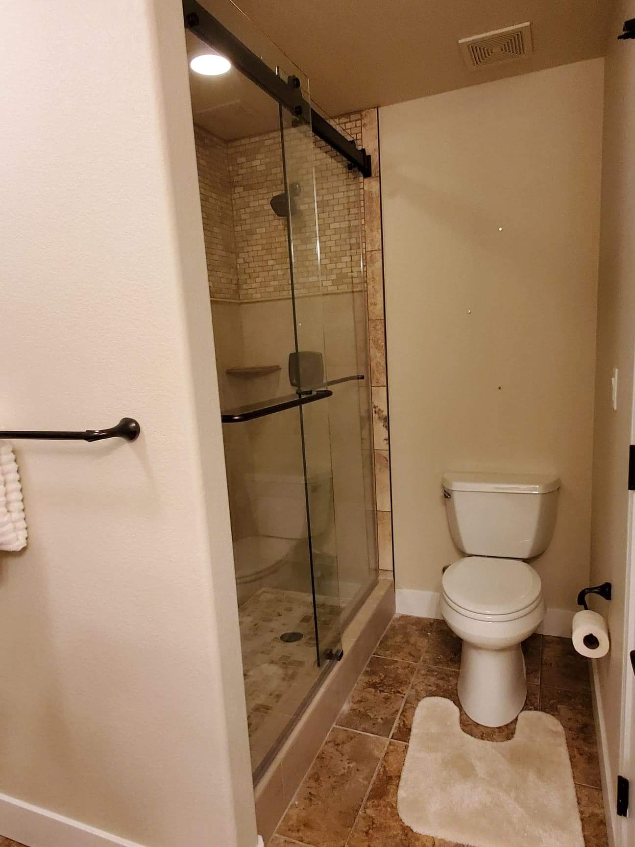 A bathroom with a toilet , shower , and towel rack.