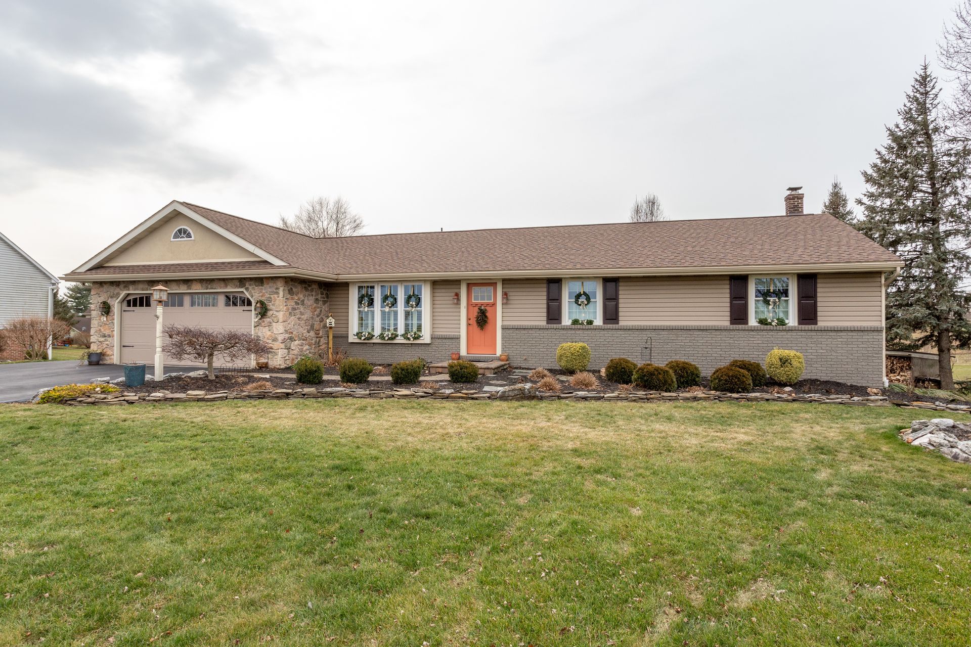 Single-story suburban house with beige siding, a front lawn, and a two-car garage