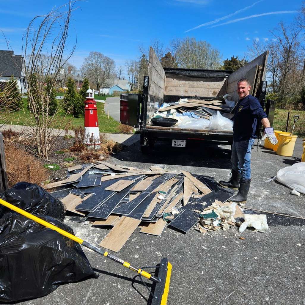 A man is standing in front of a dumpster full of garbage.