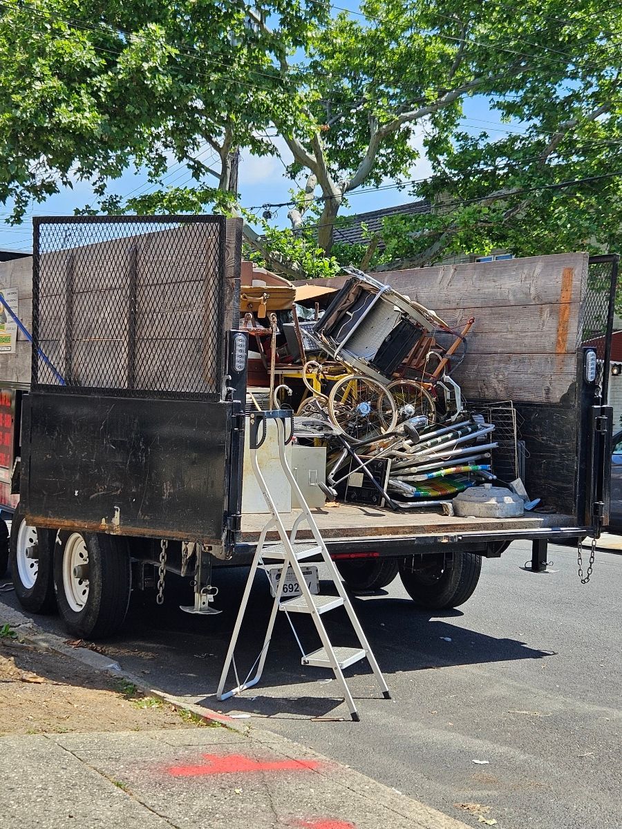 A dump truck filled with junk is parked on the side of the road.