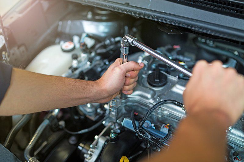 A man is working on the engine of a car with a wrench.