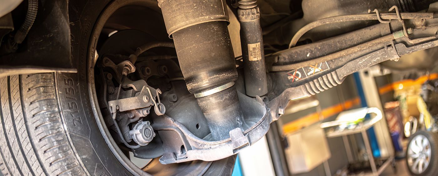 Underside of a car rear suspension with a tire, shock absorber, and brake components visible.