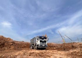 Dump truck on a construction site with brown dirt and blue sky.