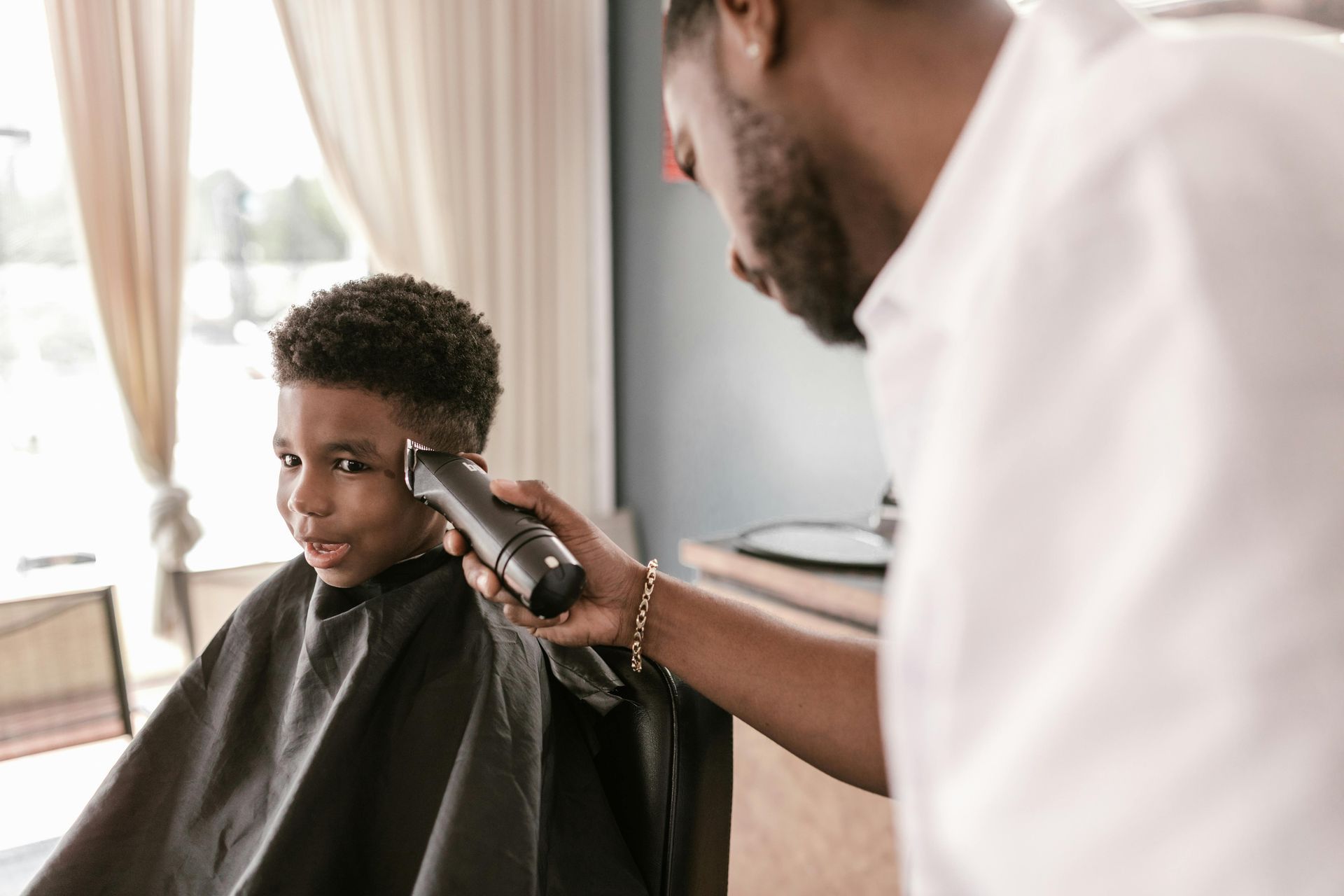 Barber trimming a client’s hair with clippers in a bright salon