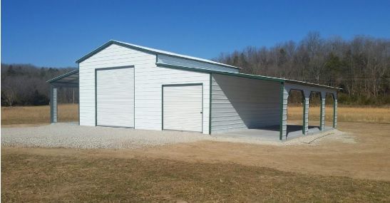 White metal garage with two doors and a covered side porch on a grassy rural lot under a blue sky