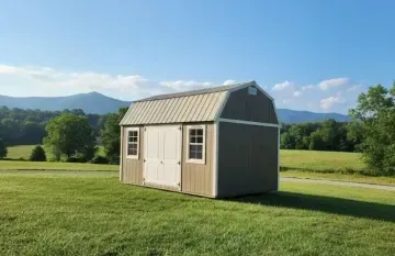 Tan shed with white doors on a sunny grassy field with mountains in the background