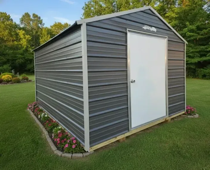 Gray outdoor storage shed with white door, sitting on a lawn with flower beds