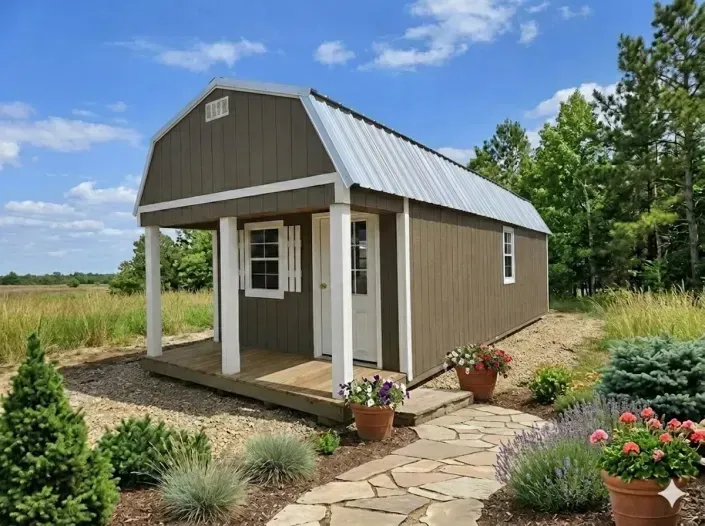 Small brown garden shed with a porch and stone path in a landscaped yard under a blue sky