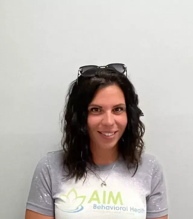 Woman with dark hair smiles, wearing sunglasses