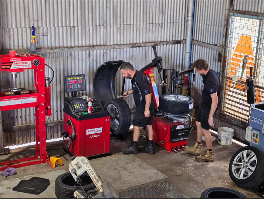Two mechanics working on tires in a garage, using machinery - Darwin Auto Mobile Care in Woolner, NT