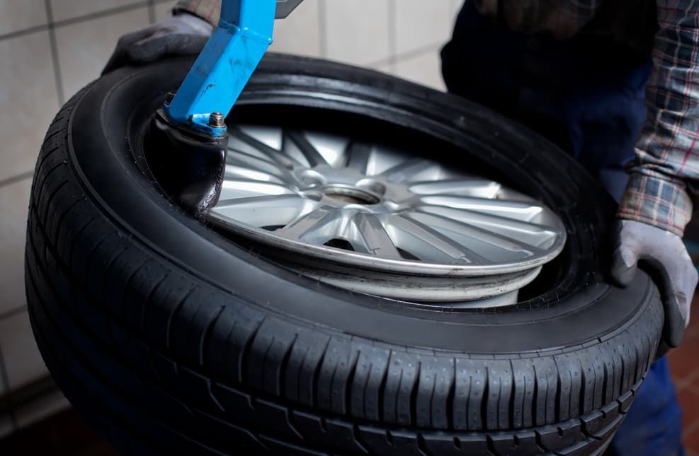 Mechanic Using A Tire Machine To Mount A New Tire Onto A Silver Rim — Darwin Auto Mobile Care in Woolner, NT