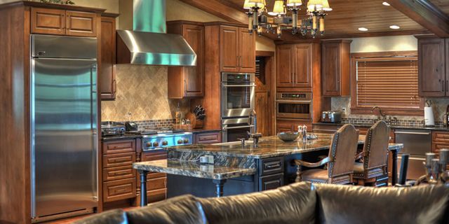A kitchen with stainless steel appliances and wooden cabinets and a couch.