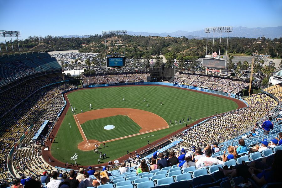 Panoramic view of Dodger Stadium with baseball field, spectators, and blue seats under a bright sky.