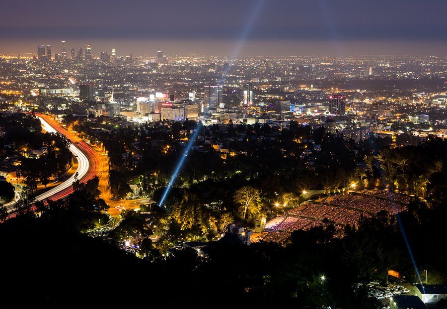 Nighttime cityscape with a bright spotlight. Roads, lights, and distant buildings.