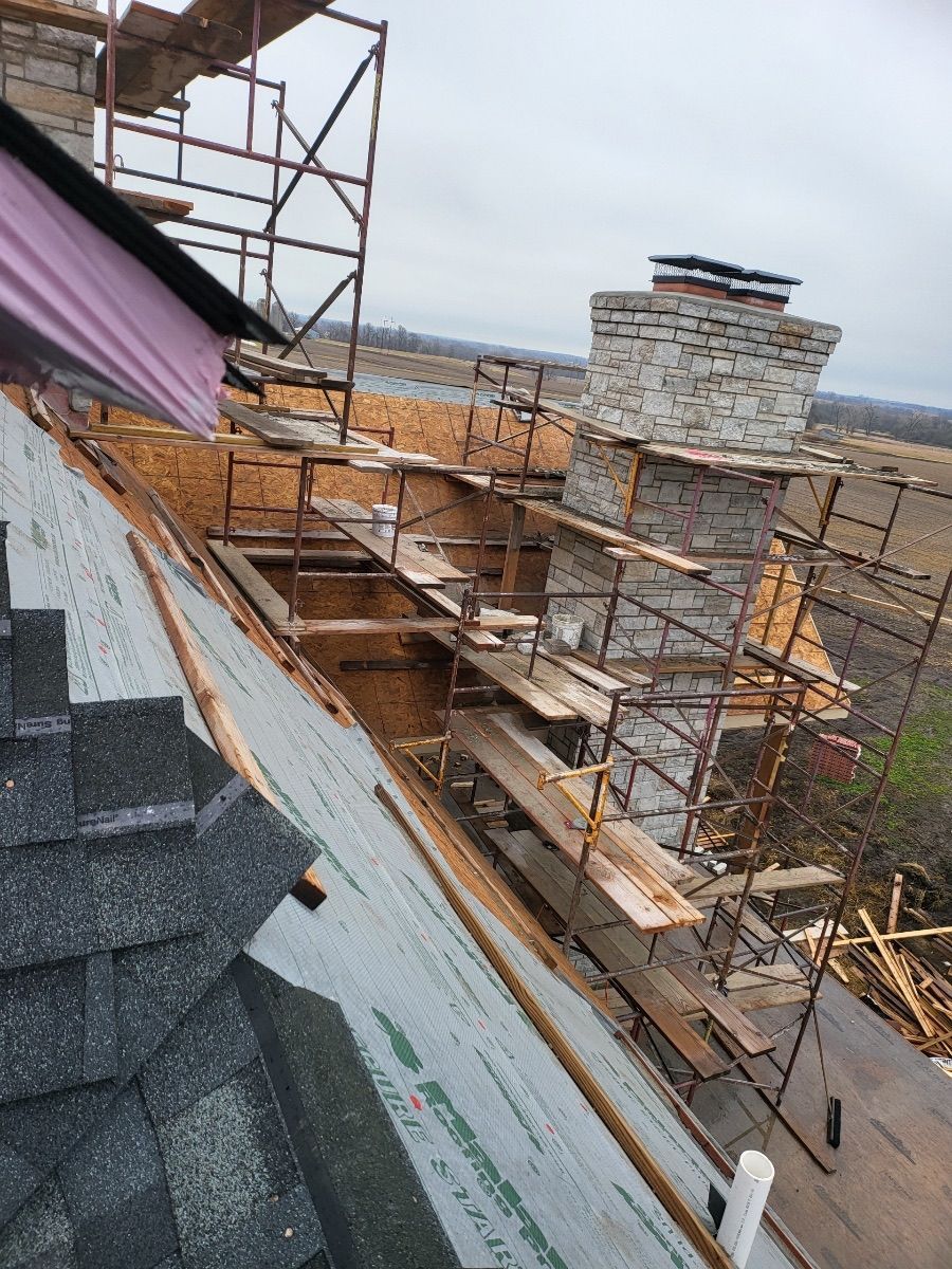 Roof under construction with scaffolding around a stone chimney.