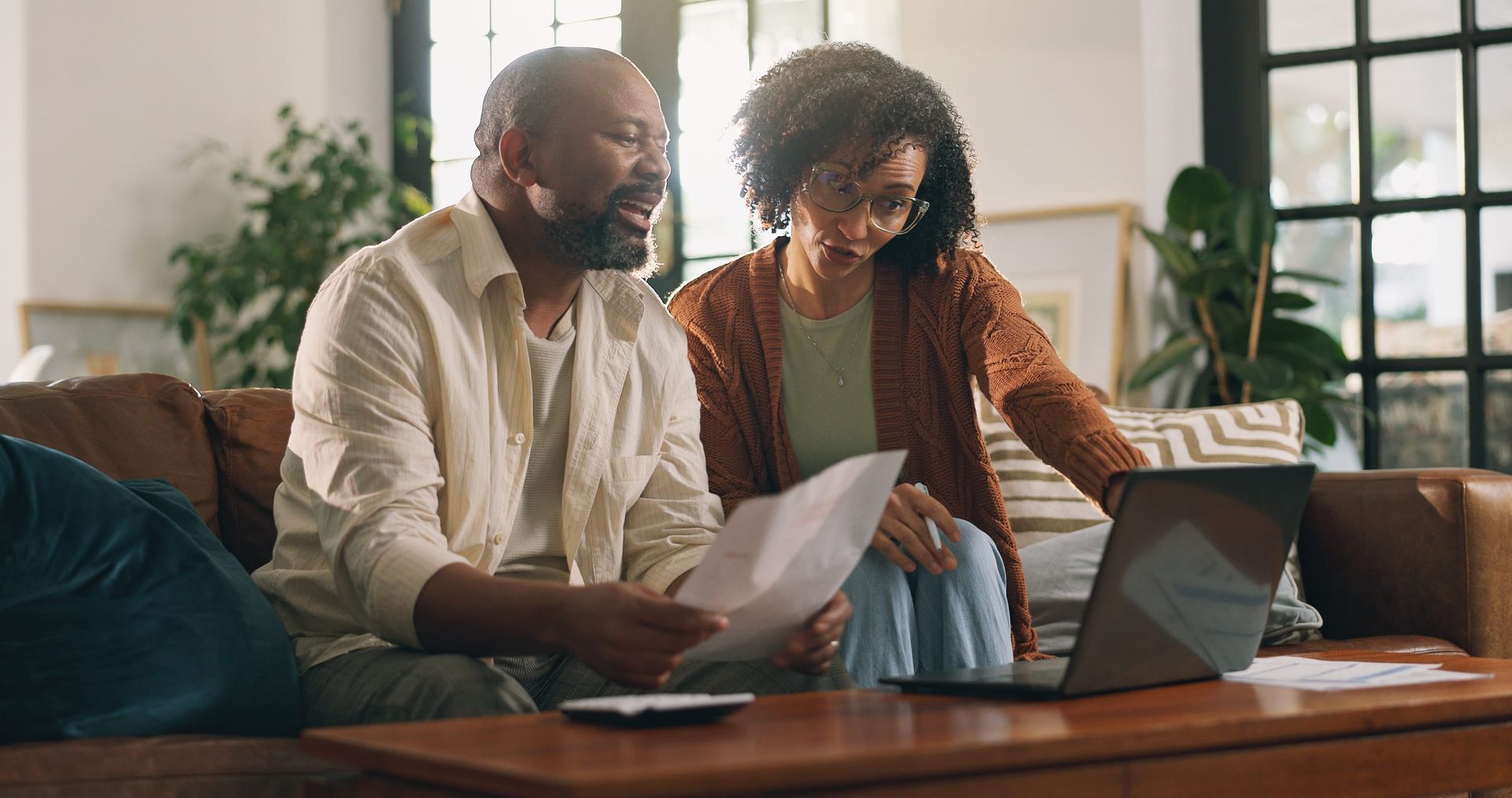 Married couple sitting together at home reviewing estate planning documents with a laptop, represent