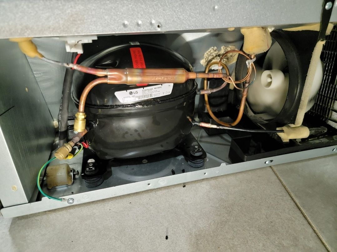 The inside of a refrigerator with the compressor visible