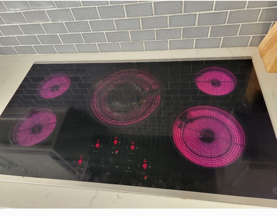 A black stove top oven with pink burners is sitting on a counter.