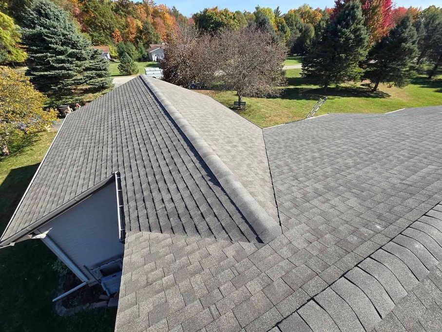 An aerial view of a roof of a house with trees in the background.