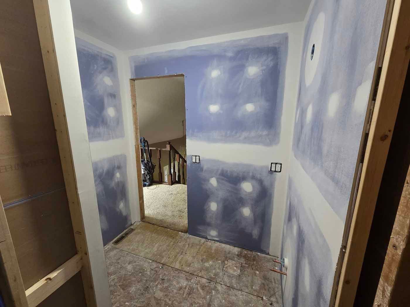 A hallway in a house under construction with drywall on the walls.