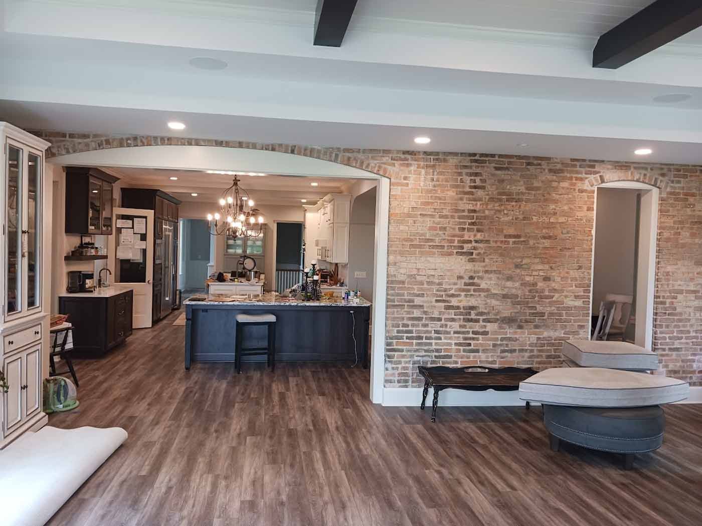 A living room with hardwood floors and a brick wall.
