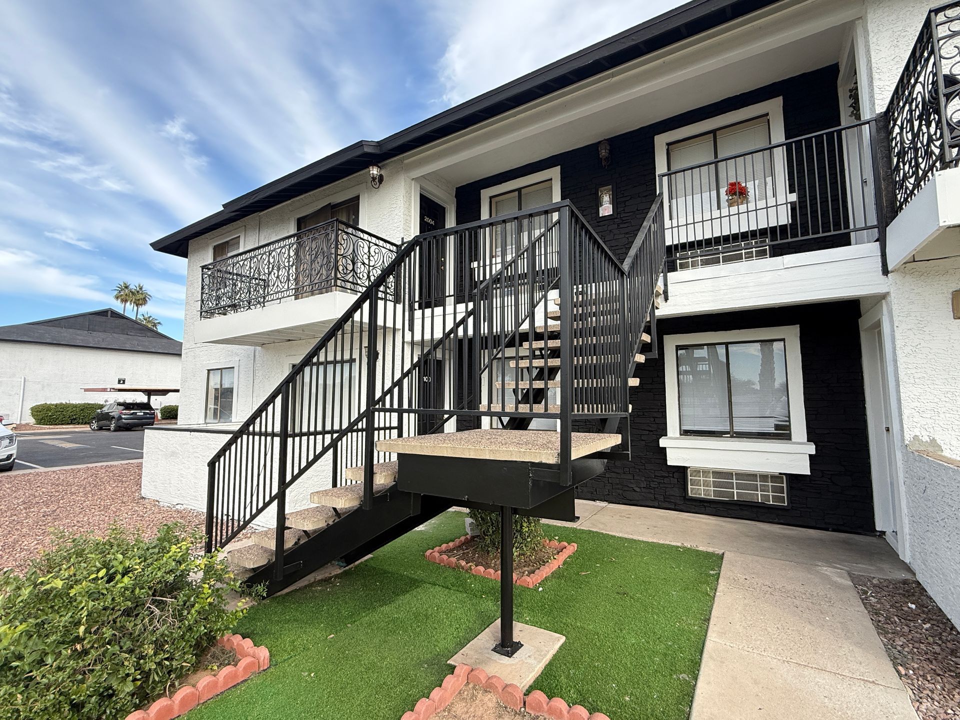 Two-story apartment building with black and white exterior, stairs, and balconies.